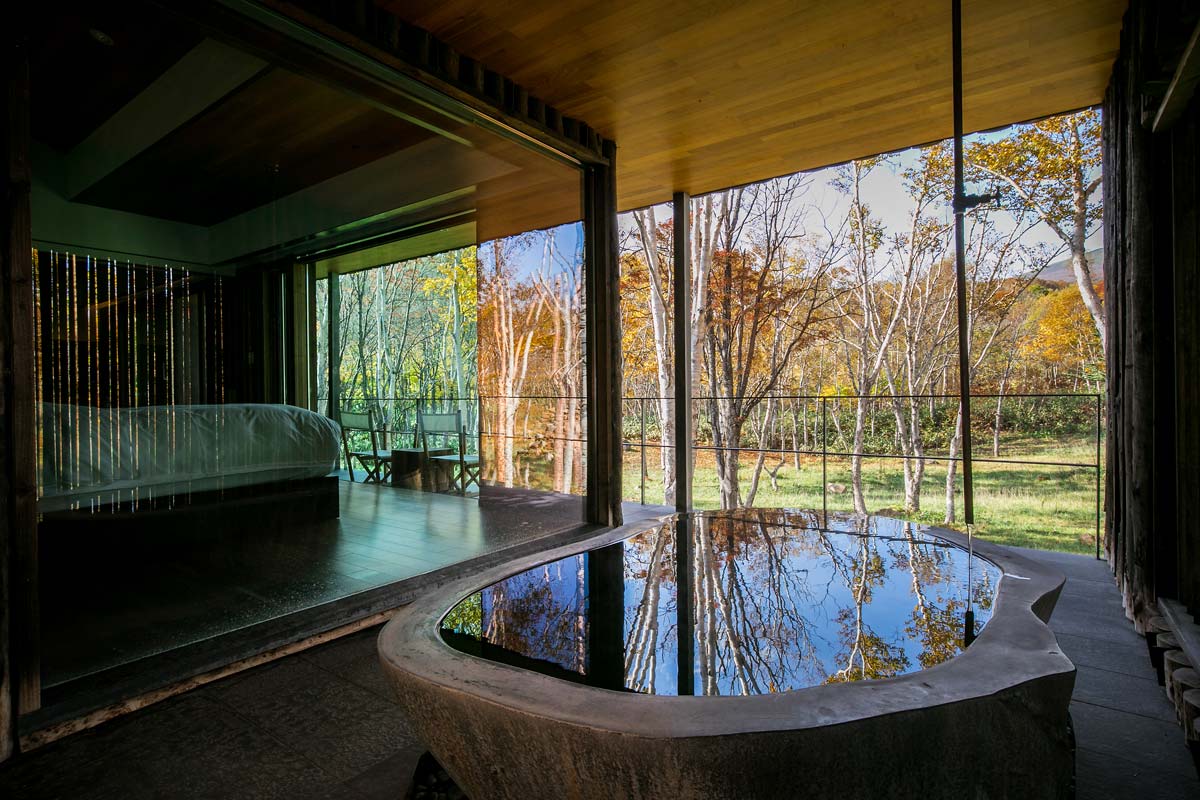 A villa's private open-air stone onsen facing the Hanazono woodland.